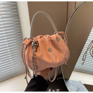 Detail of pink pleated bucket bag with rhinestone handle and heart pendant charm