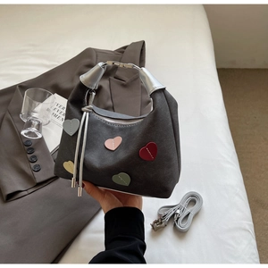 Detail of dark grey handbag with colorful heart patches and silver U-shaped metal handle