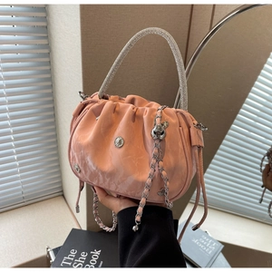 Close-up of pink pleated bucket bag with rhinestone handle and rabbit charm chain