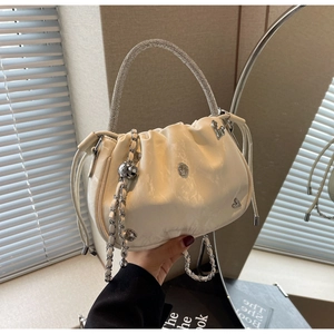 Detail of white pleated cloud bag featuring silver rhinestone handle and heart hardware
