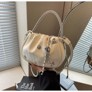 Detail of white pleated bucket bag with rhinestone handle and heart-shaped silver ornament