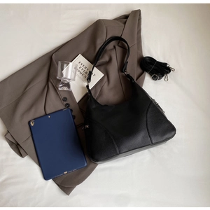 Detail view of a black pebble grain leather hobo bag with adjustable crossbody strap