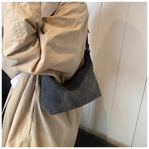 Detail view of a dark grey crescent shoulder bag with adjustable black strap and silver buckle