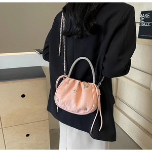 Pink pleated bucket bag with rhinestone handle and heart details worn by a model