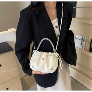 White ruched bucket bag featuring a diamond-studded handle and silver heart buckle detail