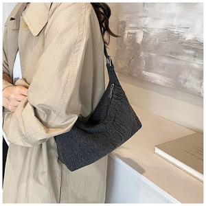 Detail of dark grey tweed shoulder bag with texture and metallic zipper on female model