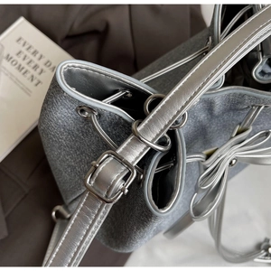 Close-up of silver-gray metallic bucket bag with leather drawstring and bow detail