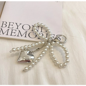 Detail of pearl bow and silver heart pendant charm on a minimalist silver backpack