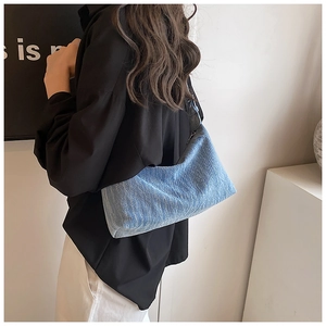 Back view of a blue denim shoulder bag on a model showing modern lifestyle style