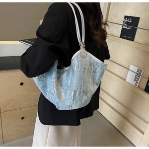 Detail der hellblauen Jeans-Tasche mit silbernen Pailletten und gewelltem Rand
