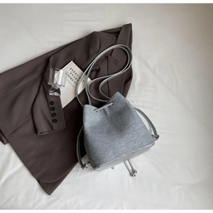 Minimalist grey felt bucket bag with silver drawstring and strap in a lifestyle setup