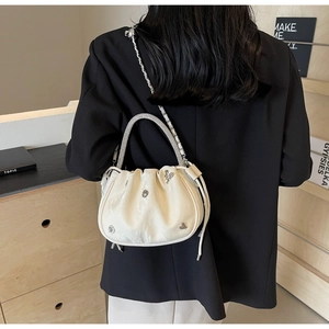 Detail view of cream pleated bucket bag with rhinestone handle and silver metal accents