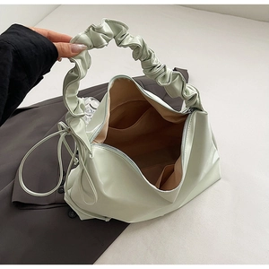Detailansicht der hellgrünen Rafftasche mit Reißverschluss und braunem Futter
