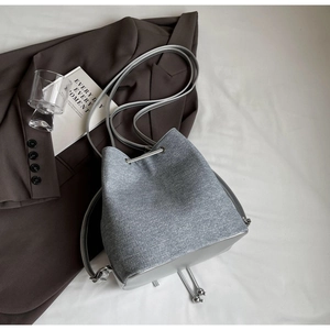 Detail of drawstring bucket bag with silver metal eyelets and grey canvas texture