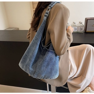 Detail of blue denim tote bag with wide shoulder strap and metal ring adjustment