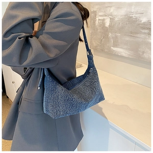 Close-up of blue tweed moon bag texture with metallic zipper and adjustable strap