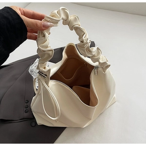 Nahaufnahme der cremefarbenen Falten-Tasche mit Wolkengriff und braunem Innenfutter
