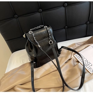 Close-up of glossy black leather mini backpack with elegant silver chain shoulder straps