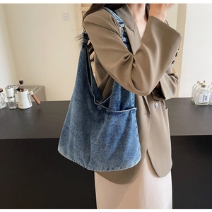 Detail of vintage washed denim tote bag showing the front pocket and white stitching texture