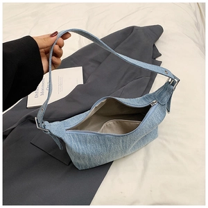 Detail view of denim hobo bag featuring adjustable metal buckle strap and inner pocket