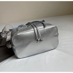 Detail of silver metallic handbag featuring sphere charms and blue textured side panels
