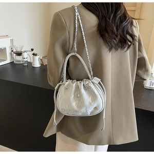 Detail of silver pleated bucket bag featuring rhinestone handle and heart metal accents