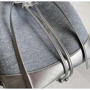 Detail of blue denim bucket bag with silver leather trim and drawstring closure