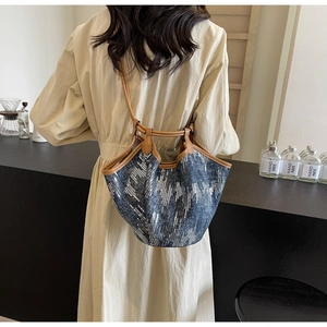 Detailaufnahme der Pailletten-Jeans-Tasche mit braunen Ledergriffen am Modell