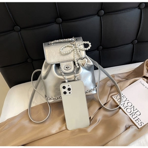 Mini silver bucket backpack with pearl bow detail and chain strap shown with a smartphone