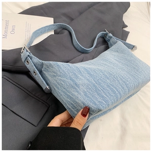 Close-up of light blue denim crescent hobo bag with adjustable eyelet metal buckle strap
