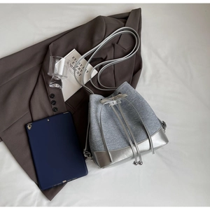 Flat lay of a grey contrast bucket bag with metallic base next to a tablet and blazer