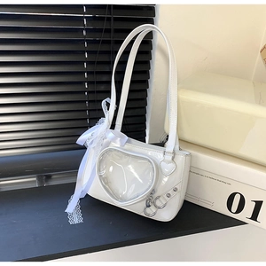 Macro detail of white heart-shaped ita bag with clear window and lace ribbon bows