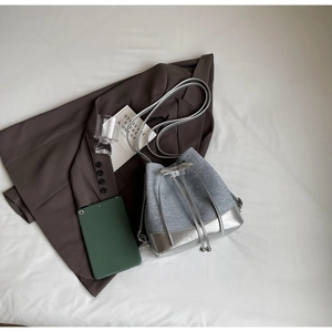 Detail of silver contrast bucket bag featuring denim texture and drawstring with beads