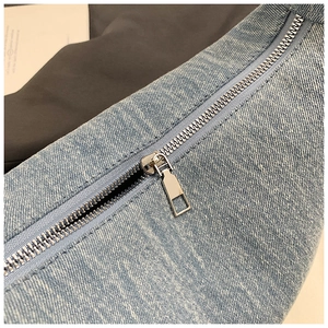 Detailed macro view of light blue denim fabric texture and silver metal zipper on bag