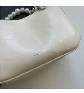 Close-up of off-white pleated leather texture and elegant pearl shoulder strap detail