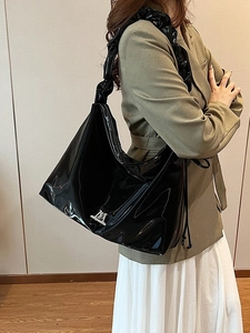 Schicke hobo-tasche aus schwarzem lackleder mit gefaltetem gurt und silber-m-logo