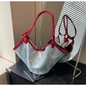 Detail der blauen Denim-Tasche mit silbernen Pailletten und roten Ledergriffen im Spiegel