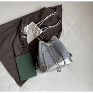 Top-down detail of bucket bag showing grey fabric and silver metallic drawstring closure
