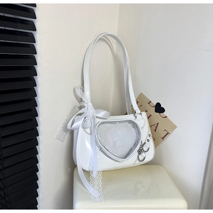 Detail of white patent leather heart-shaped window bag with lace bow decoration