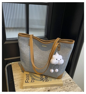 Macro detail of light blue woven tote bag with brown leather handles and cloud charm