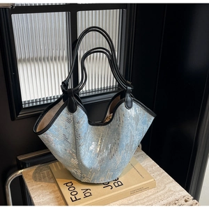 Detail der hellblauen Pailletten-Tasche mit schwarzen Lederbesätzen und Doppelgriffen