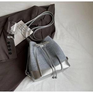 Detail of color-block bucket bag with drawstring closure and silver metallic strap