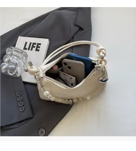 Detail view showing large pearl strap and internal space for two smartphones in cream bag