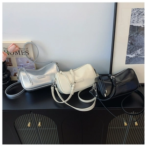 Three elegant cylindrical pillow bags in silver, cream and black on a stylish console