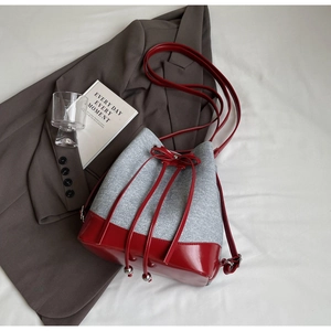 Detail of contrast bucket bag with gray knit fabric and red glossy leather base