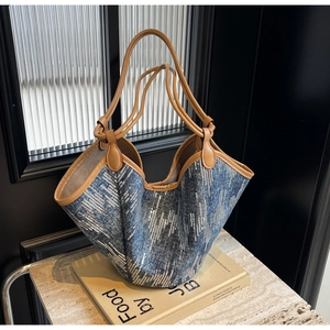 Detail der Denim-Tragetasche mit silbernen Pailletten und braunen Ledergriffen auf Marmor