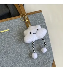 Detailed view of a plush white cloud charm with striped legs on a grey denim tote bag