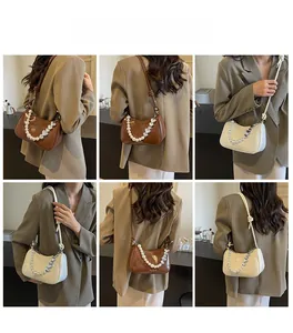 Detail of elegant pearl and heart chain strap on a glossy leather shoulder bag