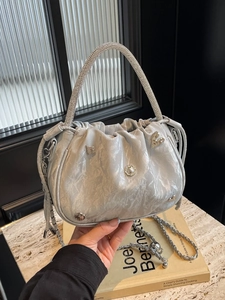 Chic ruched bucket bag with rhinestone handle and metallic charms on book background