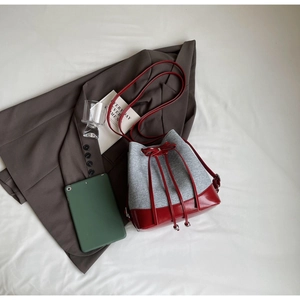 Flat lay of gray felt and red leather drawstring bucket bag with modern stationery